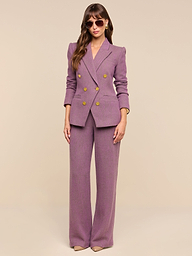 A woman stands against a plain white background wearing high-rise Livvy Straight-Leg Trousers in mauve paired with a matching double-breasted blazer, beige heels, and oversized sunglasses. Her hands are relaxed at her sides, and her long hair falls over her shoulders.