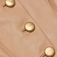 Close-up of the Mariella Leather Jacket in cappuccino leather, featuring gold buttons engraved with L’AGENCE. The buttons are sewn in a vertical line, accentuating the chic jacket’s elegant appeal.