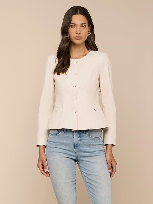 A woman wearing the Mariella Leather Jacket—a fitted, cream-colored, collarless design—paired with light blue jeans stands facing forward against a plain light background.