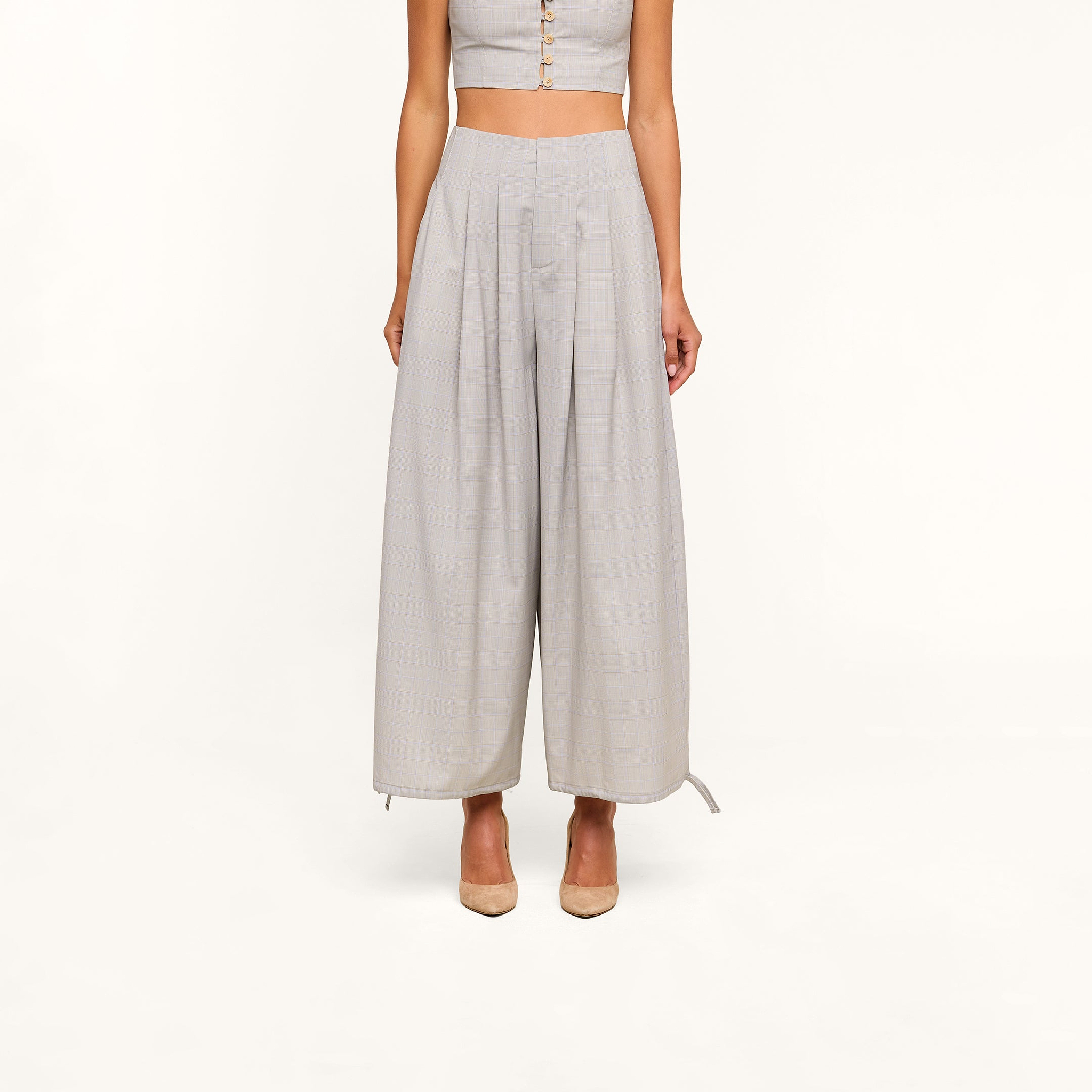 A person wearing the Ysola Pant—an ultra-high rise, wide-leg light gray wool blend—and a matching sleeveless crop top stands in nude heels against a plain white background.