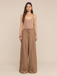 A woman stands facing forward, wearing a sleeveless tan top and the Connie Drawstring Trouser—high-rise, wide-leg pinstripe trousers with a drawstring—against a plain white background.