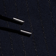 Close-up of the Connie Drawstring Trouser’s dark textured fabric, woven with diagonal metallic threads for a pinstripe effect, and featuring two black drawstrings finished with silver metal tips engraved with LAGENCE.