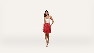 A woman stands against a plain white background, wearing a white sleeveless top, red skirt, and beige high-heeled shoes. She has one hand in her skirt pocket and is smiling slightly.