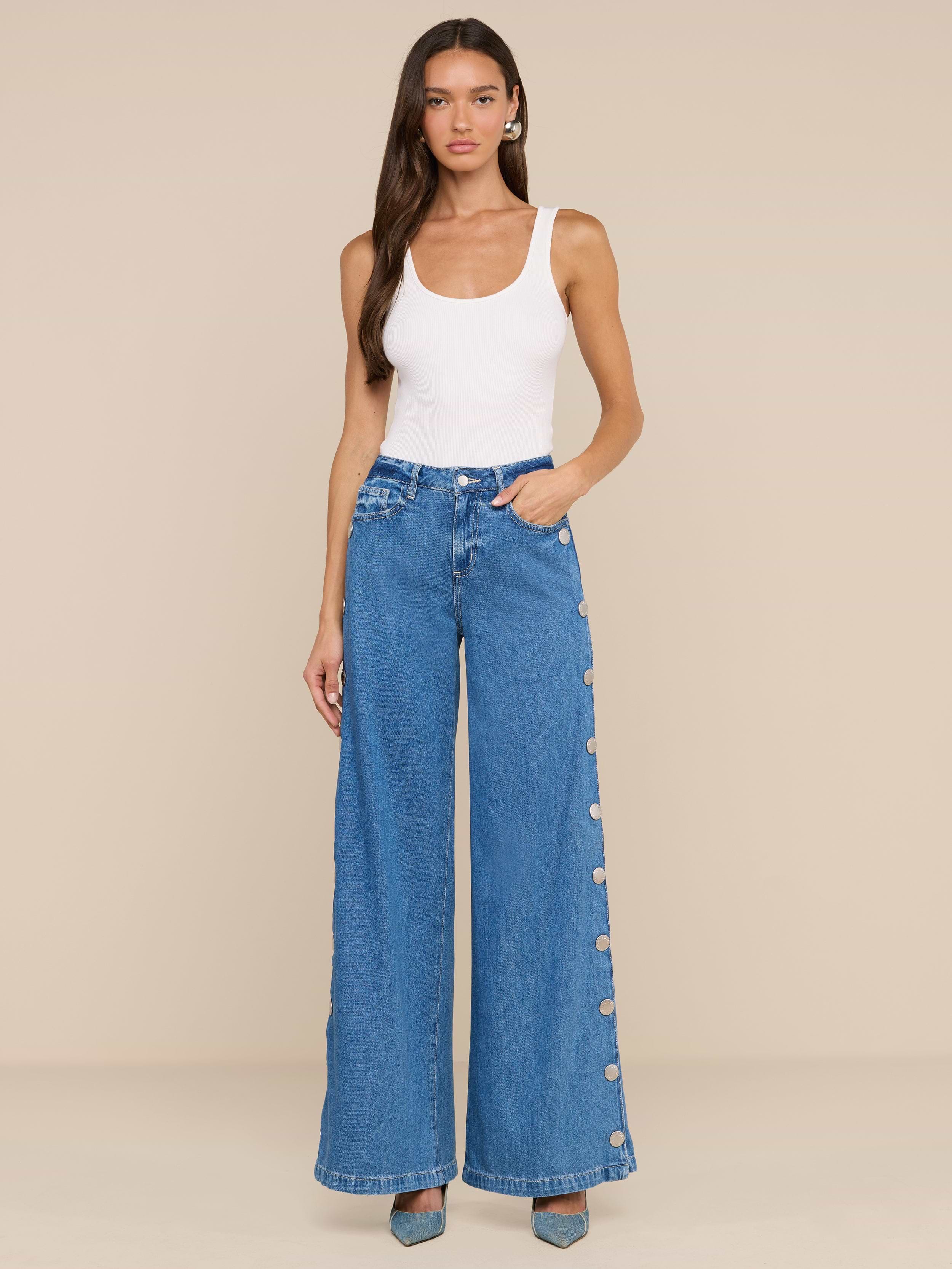 Woman standing against a plain background, wearing a white sleeveless top, Jennings Snap Wide-Leg Jean in featherweight denim with side buttons, and teal pointed-toe heels.