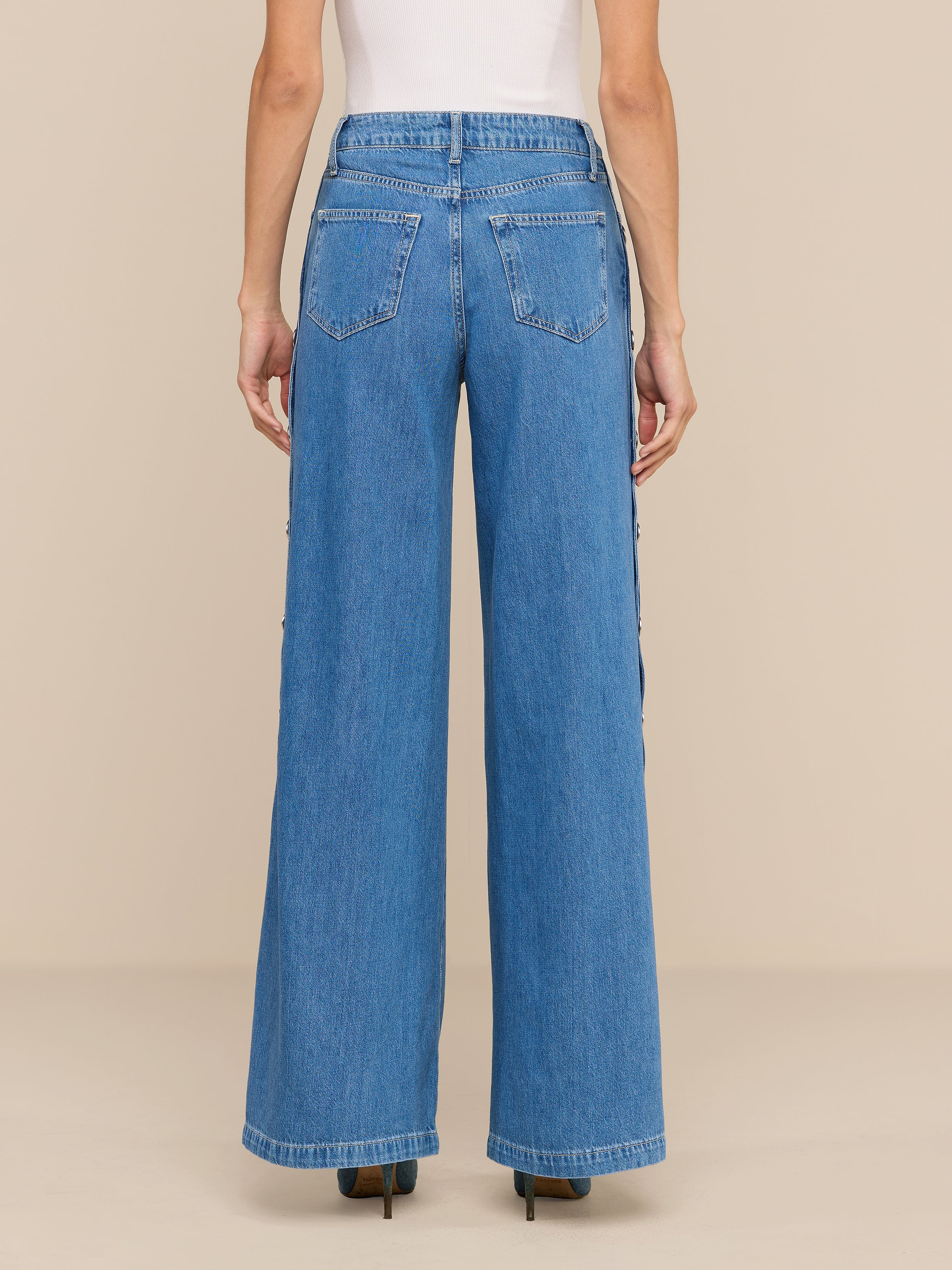A person wearing the Jennings Snap Wide-Leg Jean in blue featherweight denim and a white sleeveless top, standing facing away from the camera against a plain white background.