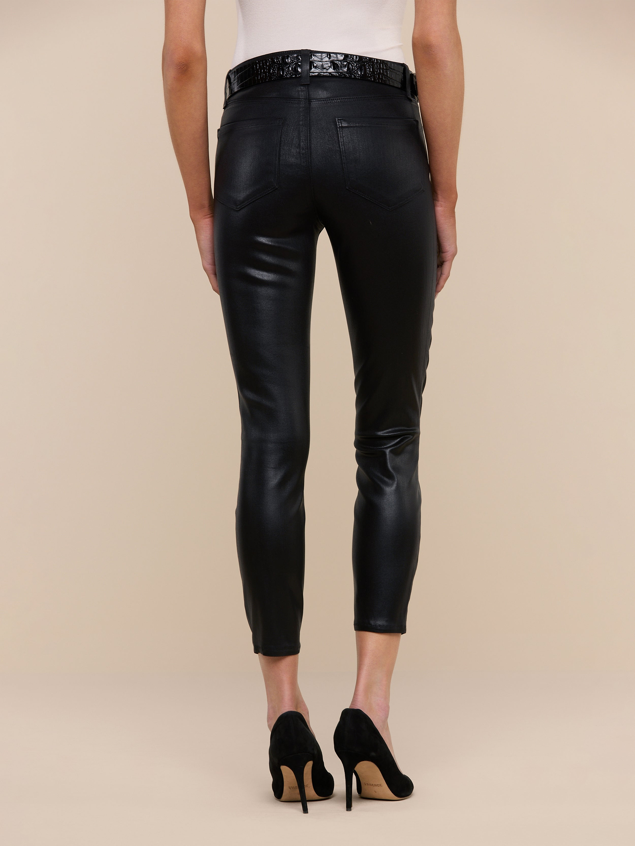A person shown from the back against a plain white background is wearing the Margot Coated Cropped Skinny Jean in black, paired with a white top and black high heels.