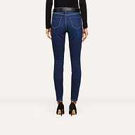 A person wearing a black long-sleeve top, high-waisted blue skinny jeans, and black high heels is shown from the back, standing against a plain white background. The sleek outfit highlights modern fashion trends.