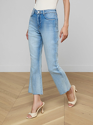 A person wearing the Kendra Cropped Flare Jean, a tan sleeveless top, a brown belt, and beige high-heeled sandals stands against a plain white background. Their head and lower arms are not visible.