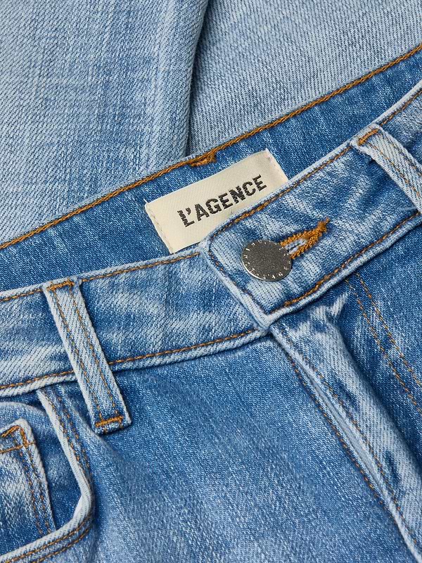 Close-up of light wash denim Kendra Cropped Flare Jean featuring an LAGENCE brand label near the waistband and a metallic button closure, highlighting its stylish cropped flare silhouette.