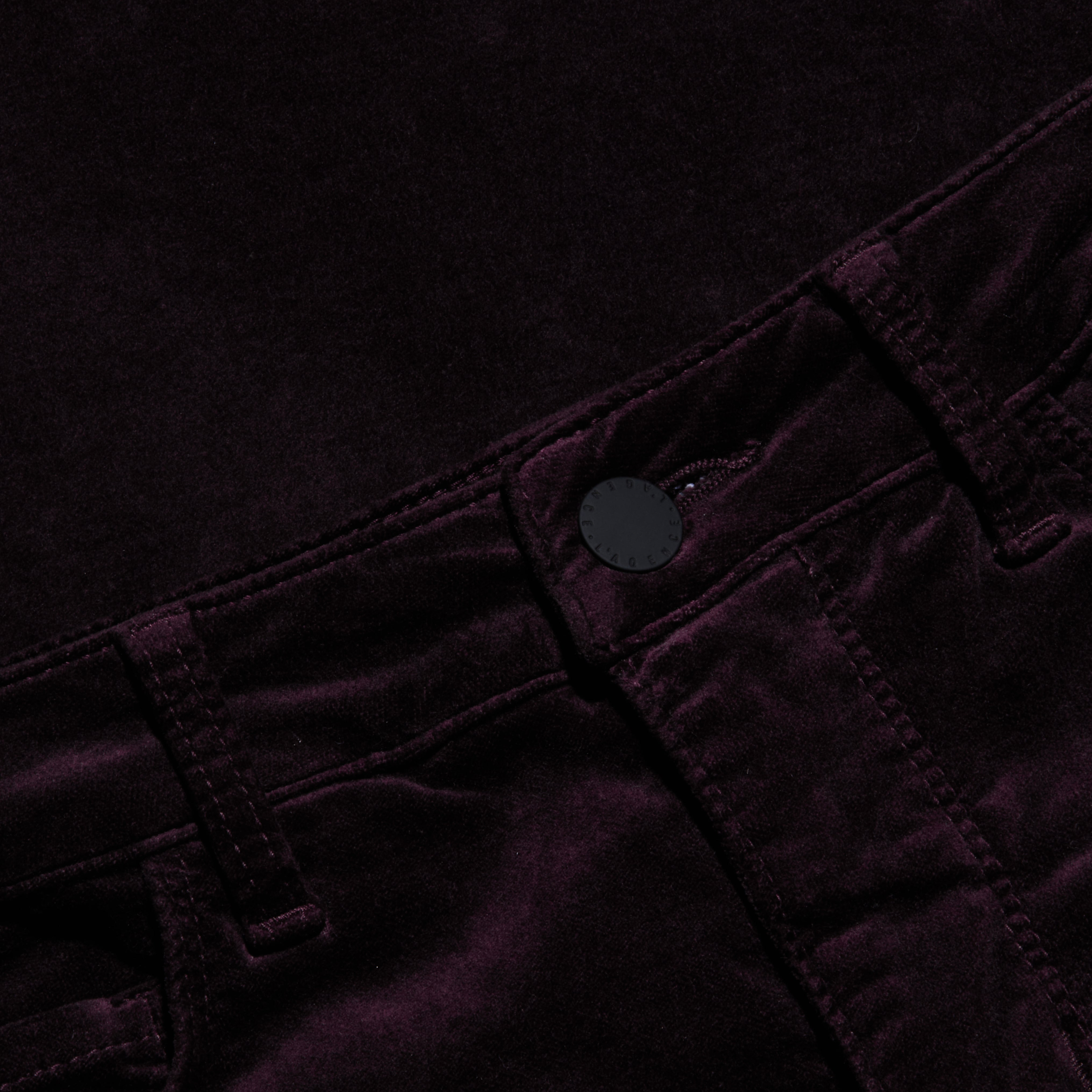 Close-up of the Stevie Velvet Jean, crafted from a soft, dark-colored velvety fabric, featuring a high-rise waistband, stitched belt loops, and a black front button.
