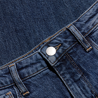 A close-up of blue denim jeans highlights the waistband, metal button, belt loops, and visible stitching against a coordinating denim background.