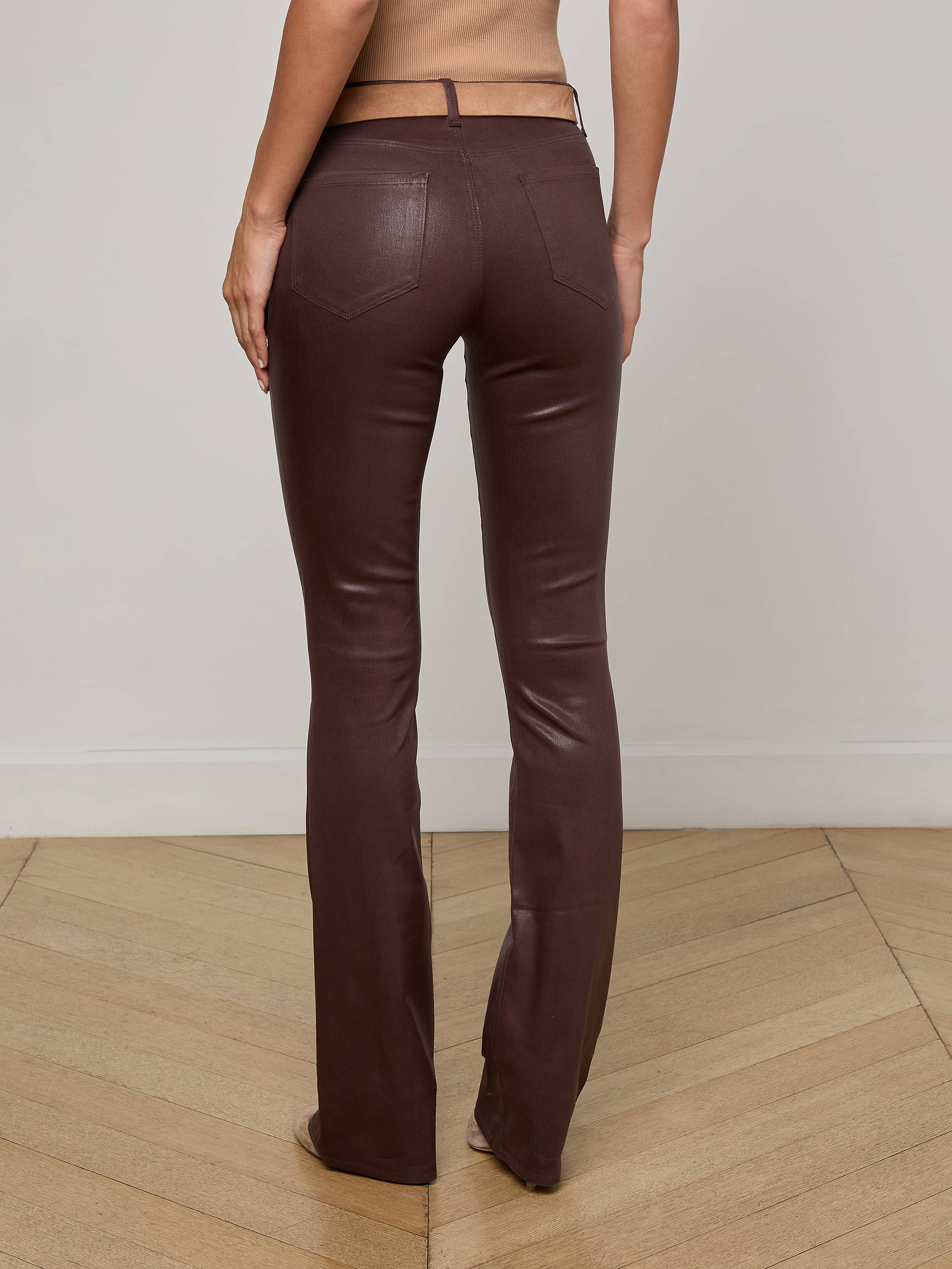 A person is shown from the back, standing against a plain light background, wearing the Selma Coated Bootcut Jean in a high-waisted, chocolate brown style.
