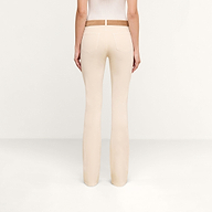 A person is shown from the back, standing in a plain, light-colored room, wearing the Selma Coated Bootcut Jean and a white top.