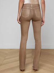A person is shown from the back, lower half only, against a plain white background, wearing the Selma Coated Bootcut Jean in light brown, styled with a white long-sleeve top and a brown belt.