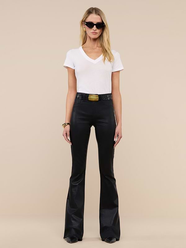 A person stands against a plain white background wearing sunglasses, a white V-neck T-shirt, the Marty Coated Flare Jean, a wide belt with a gold buckle, and black shoes.