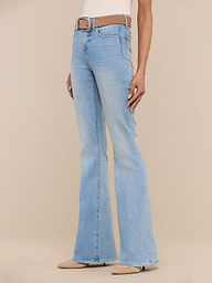 A person wearing the Marty Flare Jean in light blue, styled with a brown belt and beige pointed-toe shoes, stands against a plain white background. The upper body is mostly out of frame.