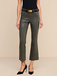 A person wearing the Kendra Coated Cropped Flare Jean in ash olive green, paired with a black top, black high heels, and a black belt featuring a large rectangular buckle, stands against a plain white background.