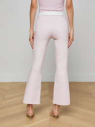 Model wearing the Kendra Coated Cropped Flare Jean in light pink, styled with a matching belt and heeled sandals, shown from the back against a plain white background.