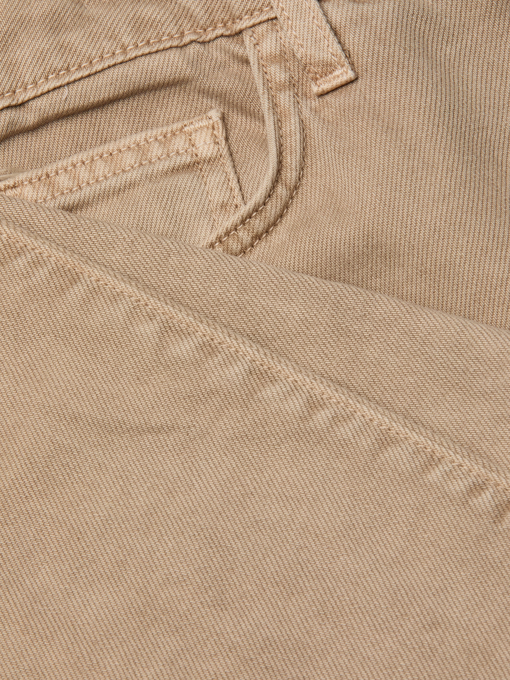 Close-up of the neutral tan denim fabric of the Wanda Cropped Wide-Leg Jean, highlighting a jeans pocket and detailed stitching, with one section of the material folded over the other.