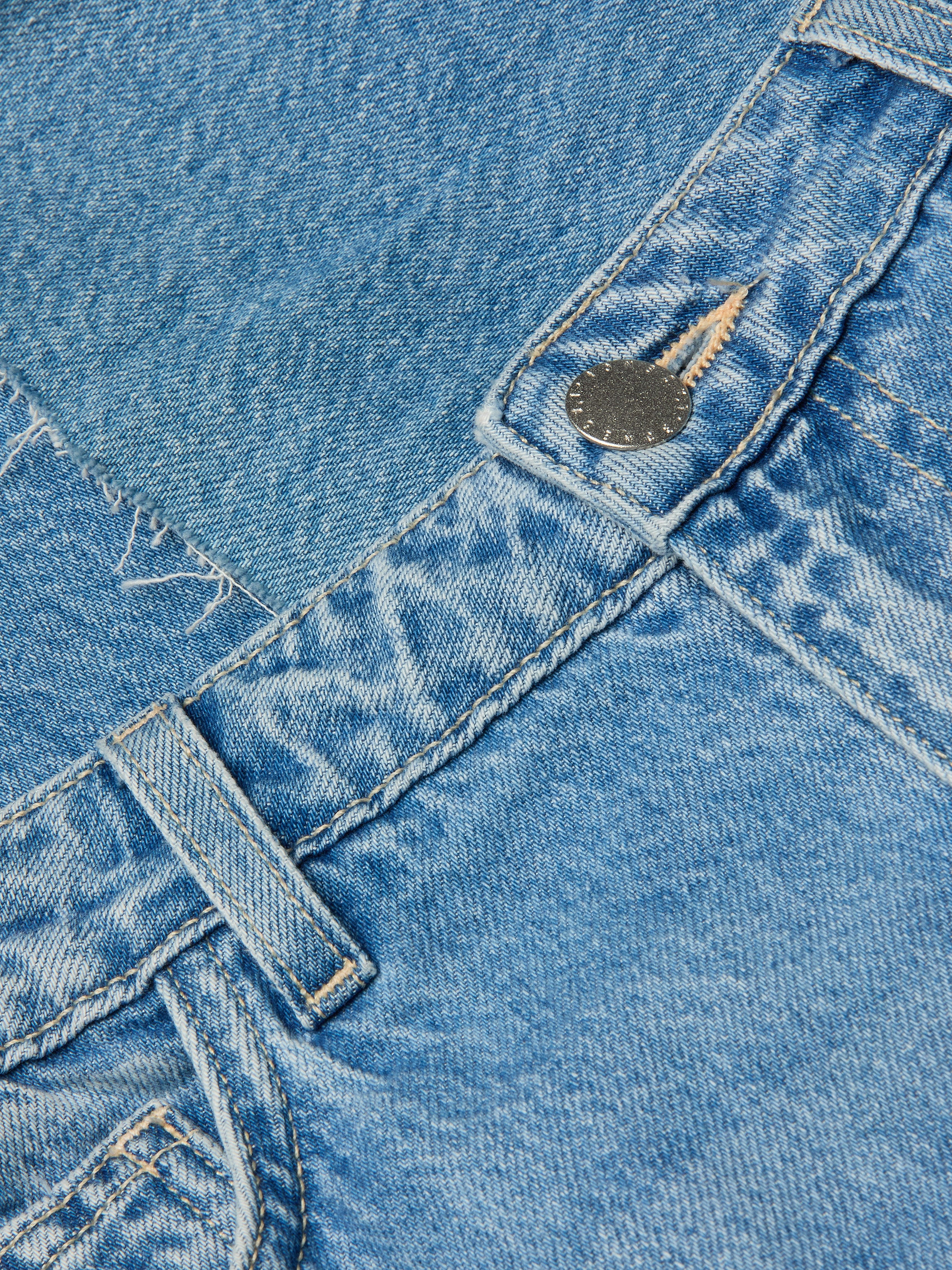 Close-up of the Wanda Cropped Wide-Leg Jean in light blue, crafted from 100 cotton denim, featuring a belt loop, metal button, visible stitching, and a pocket with frayed detailing.