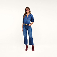 A woman stands with one hand in her pocket against a plain white background, wearing the Wanda Cropped Wide-Leg Jean, paired with red boots, sunglasses, and a black belt.