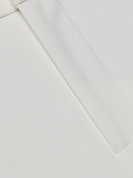 Close-up of the Rebel Trouser white stretch fabric, featuring two seams intersecting at an angle to showcase the texture and detailed stitching.