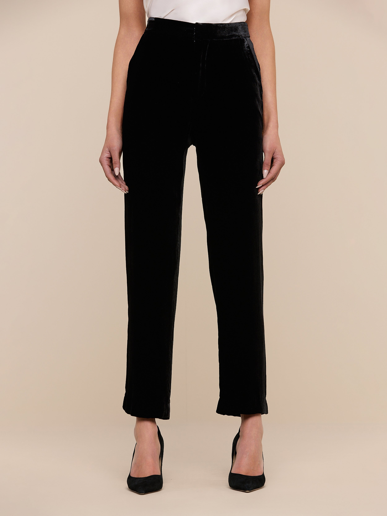 A person is wearing the Rebel Velvet Trouser in black with black heels, standing against a plain white background with their arms relaxed at their sides. Their face is not visible in the image.