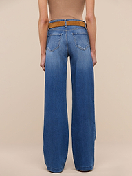 A person stands facing away against a plain white background, wearing a tan sleeveless top with a brown belt and tall wide-leg blue Clayton Wide-Leg Jeans made from REPREVE woven denim.