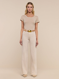 A woman stands facing forward in a beige short-sleeve top, the Clayton Wide-Leg Jean in stretch denim with a belt, and beige shoes, against a plain white background.