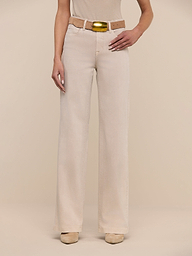A person wearing the Clayton Wide-Leg Jean in beige, paired with a matching beige shirt and a tan belt with a gold buckle, stands against a plain white background. Their head is not visible in the image.