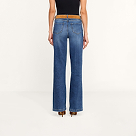 A person wearing the Clayton Wide-Leg Jean in blue, paired with a black sleeveless top, brown belt, and brown heeled shoes, is standing with their back to the camera against a plain white background.