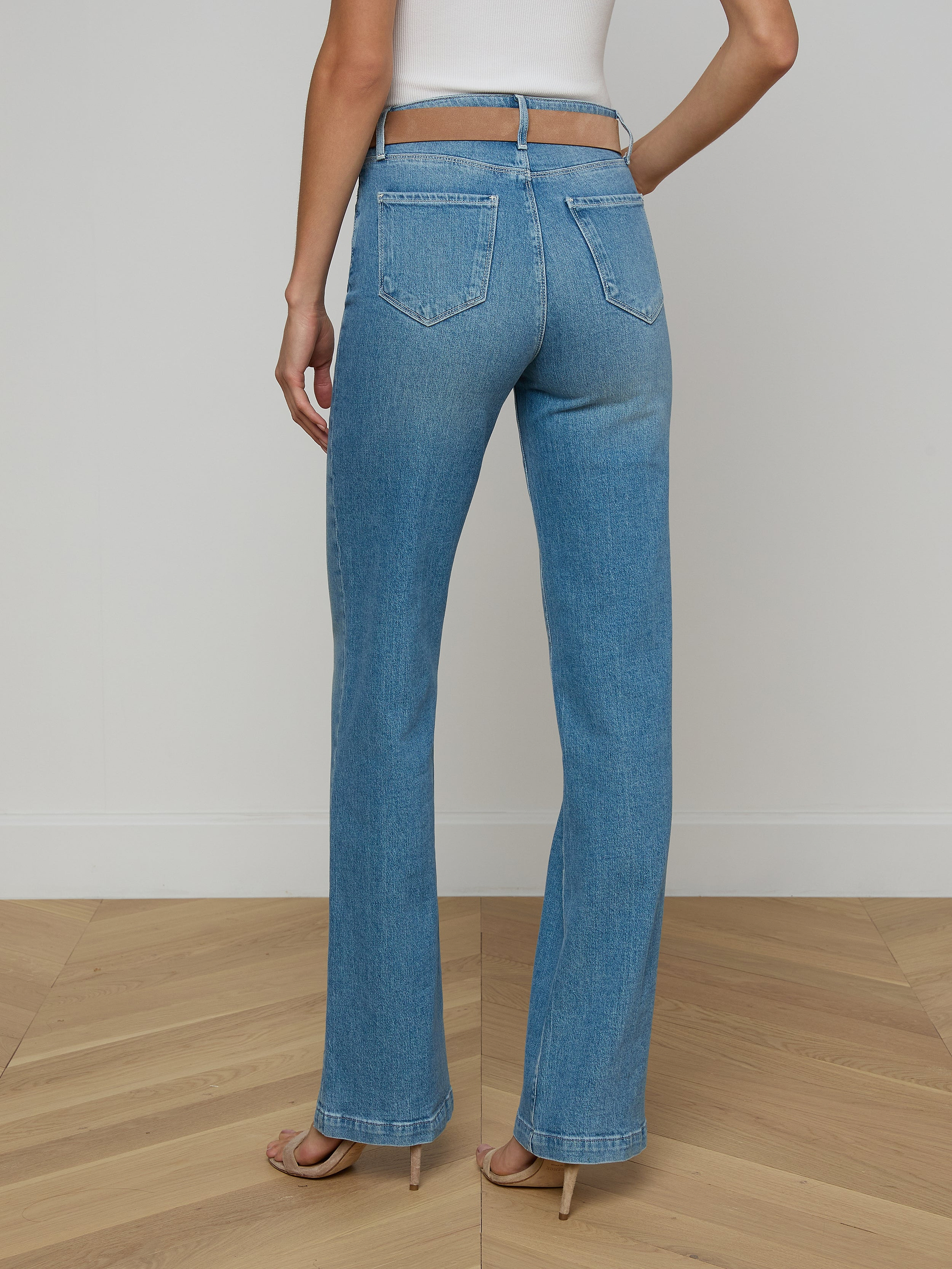 A person stands facing away, wearing the Clayton Wide-Leg Jean in light blue high-rise denim with a white top against a plain white background.