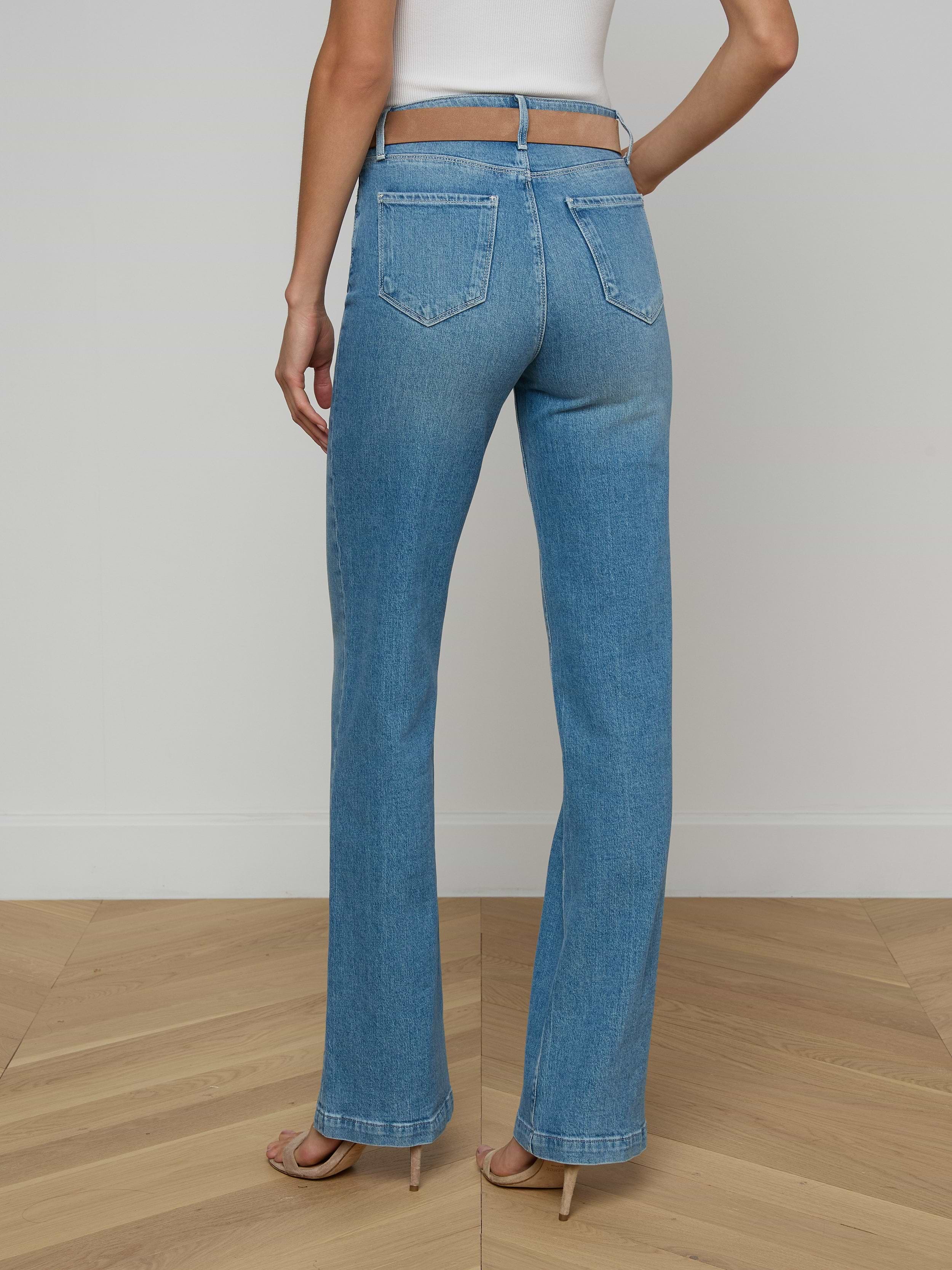 A person stands facing away, wearing the Clayton Wide-Leg Jean in light blue high-rise denim with a white top against a plain white background.