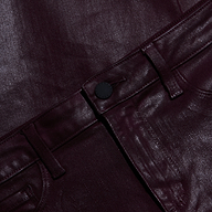 Close-up of shiny, dark burgundy metallic pants showing the waistband, belt loops, button, and part of the front pocket. The glossy fabric has a striking finish.