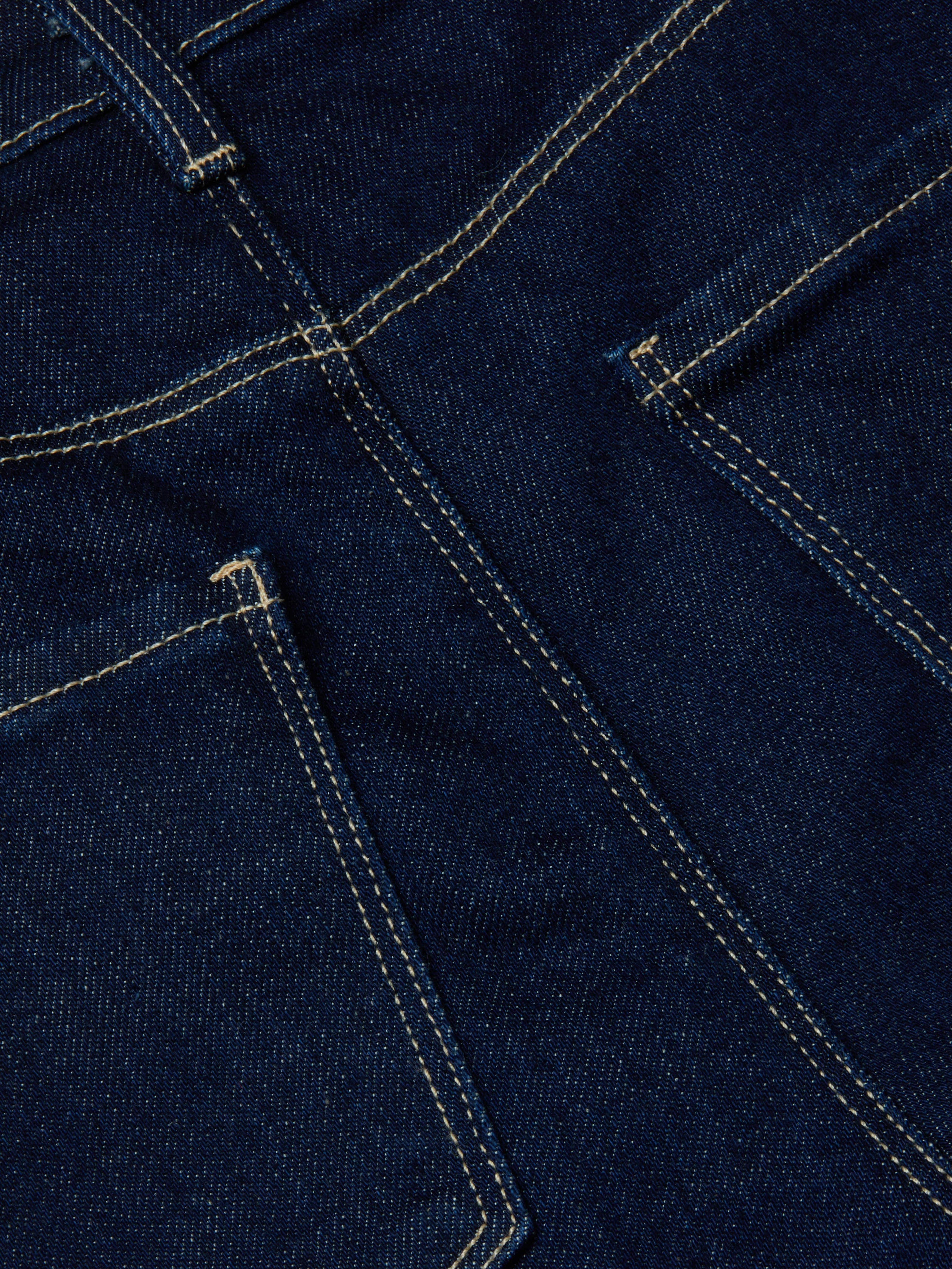Close-up of the Clayton Wide-Leg Jean in dark wash denim, featuring two pockets and double-stitched yellow seams that showcase the fabric texture and construction details of this high-rise style.