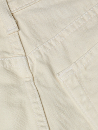 Close-up of cream-colored all-cotton denim fabric showing stitching, a seam, and part of the Clark Distressed Jean Short pocket.