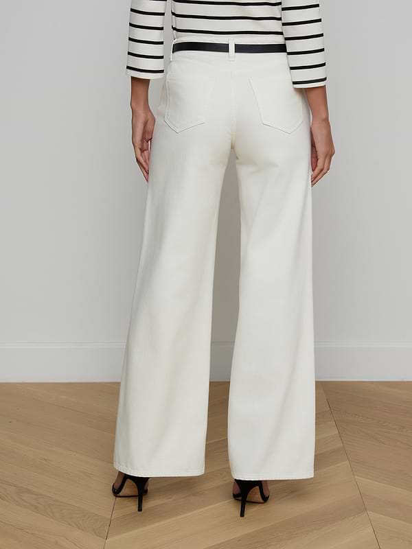 A person is shown from the back against a plain background, wearing high-rise Alicent Wide-Leg Jean in white paired with a black-and-white striped top and black heels.