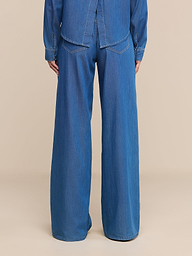 Wearing the Alicent Wide-Leg Jean and a matching denim shirt, a person is shown from the back standing against a plain white background.
