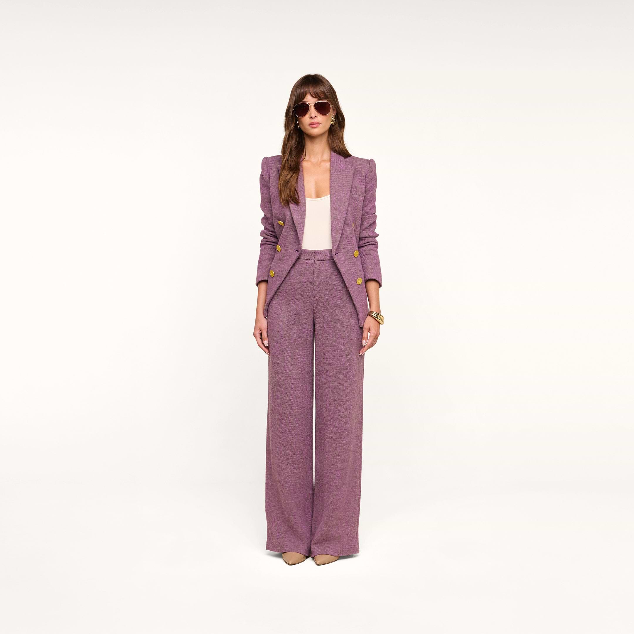 A woman stands against a plain white background wearing the Livvy Straight-Leg Trouser in mauve, paired with a light pink top and beige heels. She has long brown hair, wears sunglasses, and keeps her hands by her sides.