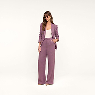 A woman stands confidently with one hand in her pocket against a plain, light background, wearing the Livvy Straight-Leg Trouser in mauve, paired with a white top, sunglasses, and beige heels.