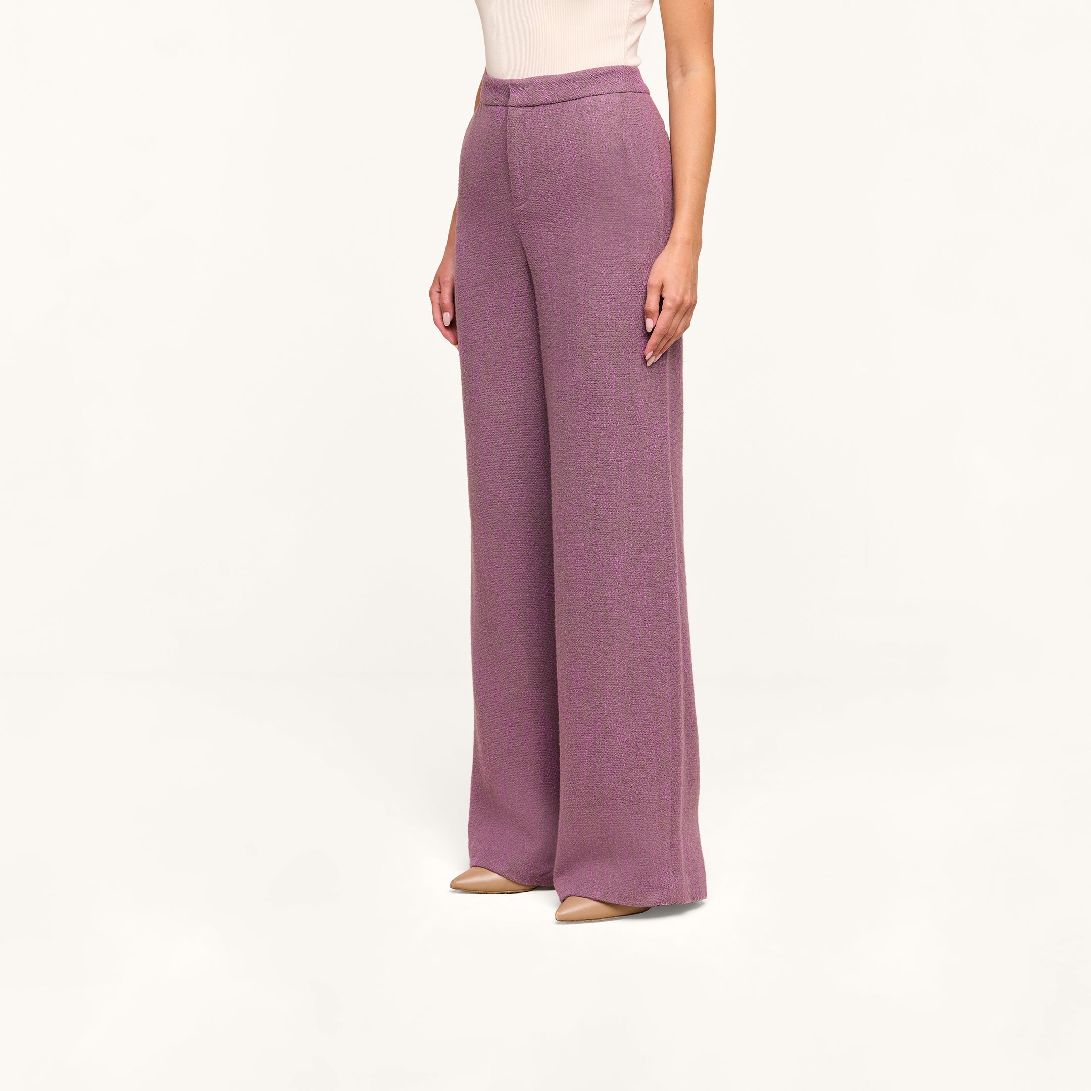 A person wearing the Livvy Straight-Leg Trouser in a high rise, wide-leg purple herringbone style with beige heels stands against a plain white background. Their upper body is partially visible.