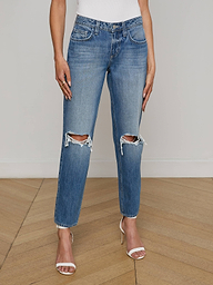 Wearing the Nevia Slouchy Straight-Leg Jean in a blue wash with ripped knees, paired with a white top and nude high-heeled sandals, this person stands against a plain white background.