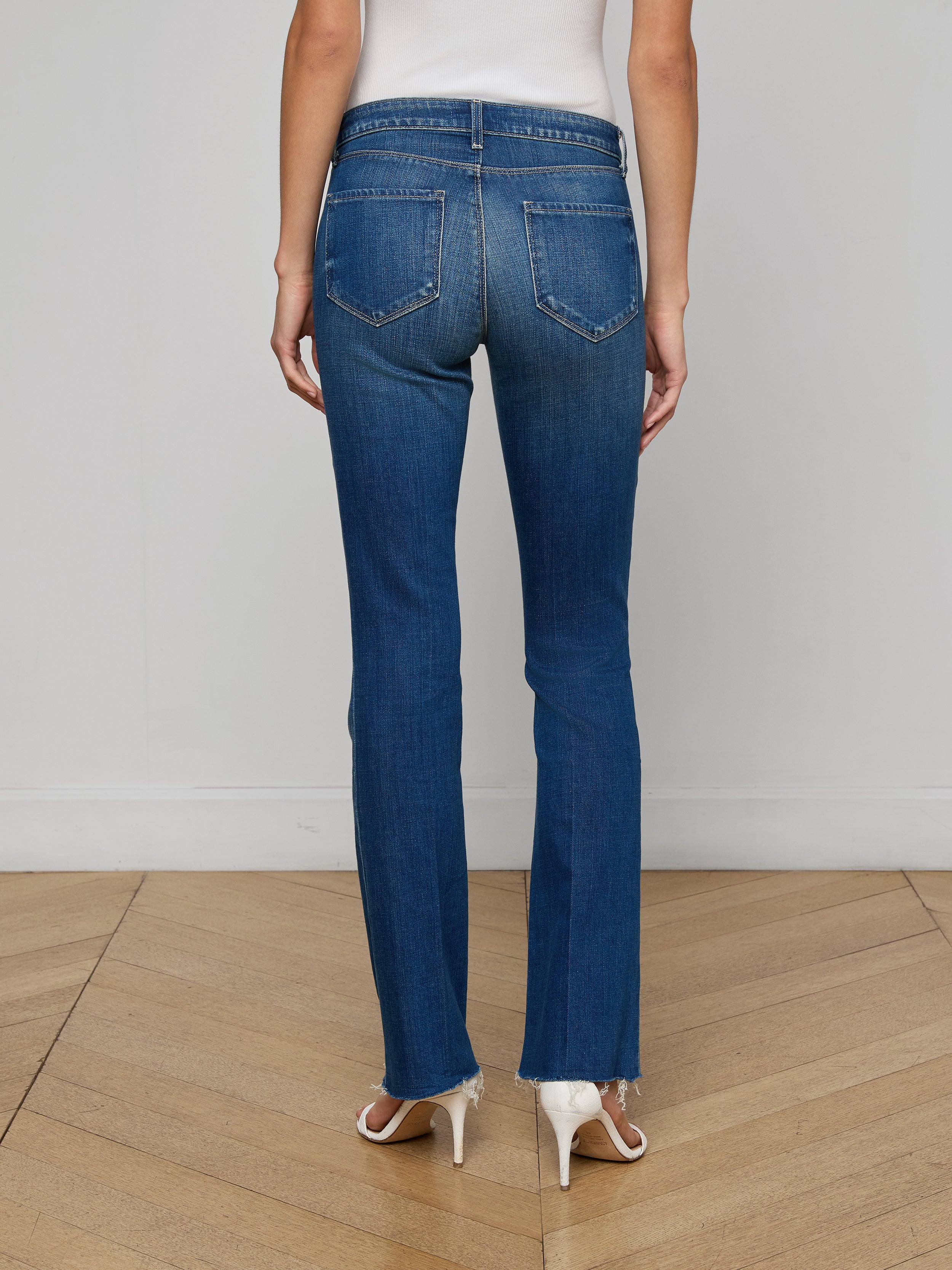 A person wearing the Sneeki Low-Rise Straight-Leg Jean stands facing away from the camera, showcasing the back pockets of the jeans against a plain, light background while paired with tan heels.
