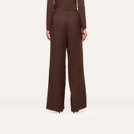 Wearing the Nova Pleated Wide-Leg Pant, crafted from a fluid suiting fabric in an ultra high rise and wide-leg silhouette, a person in a matching long-sleeve top stands facing away against a plain, light background.