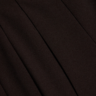 Close-up of black twill fabric with visible diagonal ribbing and seams, suggesting tailored clothing such as trousers or a skirt. The texture and folds create subtle shadows.