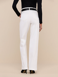 A person stands facing away from the camera, wearing the Scottie Wide-Leg Jean in white, featuring a high-rise waistband. The jeans are styled with a black belt and black top against a plain white background.
