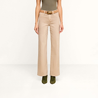 A person wearing the Scottie Coated Wide-Leg Jean in beige, styled with a brown belt, paired with a fitted olive sleeveless top and olive green boots, stands against a plain white background.