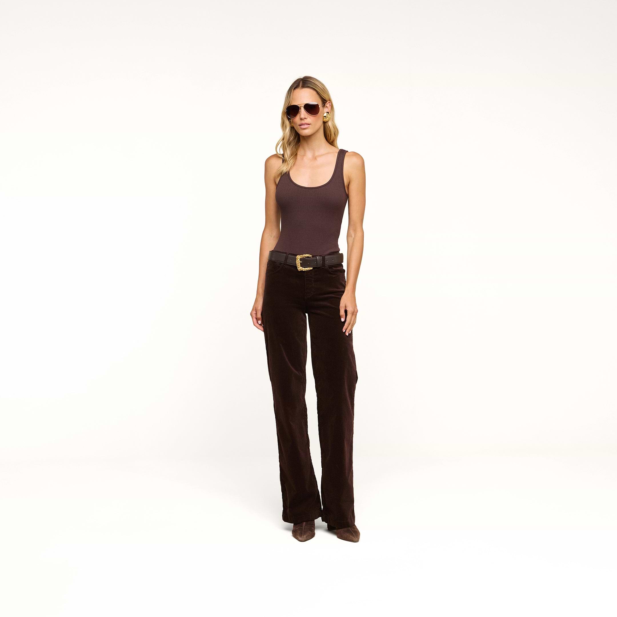 A woman in sunglasses wears a brown tank top and the Scottie Velvet Wide-Leg Jean with a contoured waistband, paired with brown shoes, standing against a plain white background.