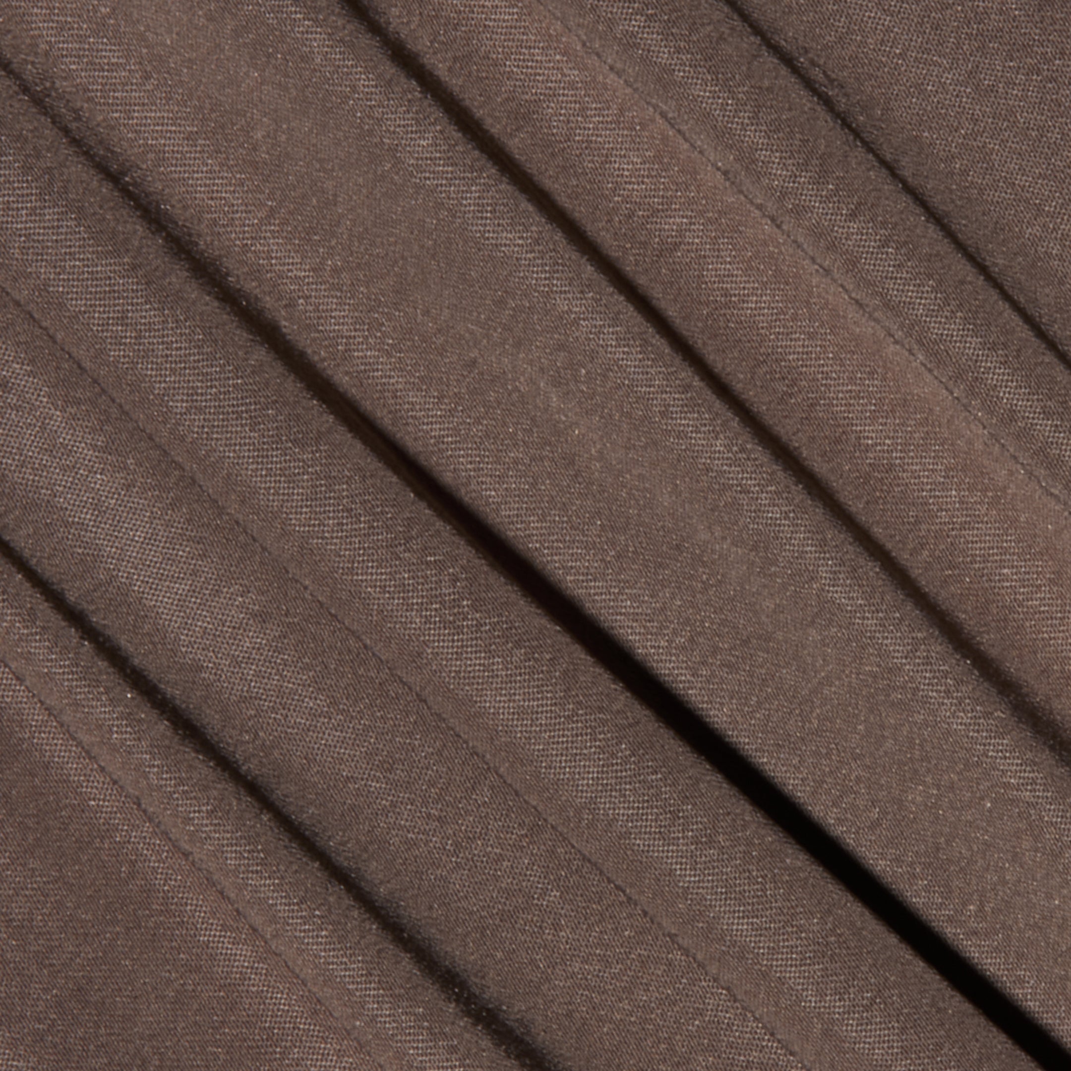 Close-up of the Palmer Satin Pant in brown, featuring diagonal pleats that highlight its soft satin texture and subtle weave pattern.