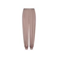 The Palmer Satin Pant, shown on a plain white background, features a light brown hue, high-rise fit, front pleats, and gathered cuffs at the ankles in a chic balloon silhouette.